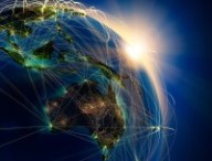 Highly detailed planet Earth at night, lit by the rising sun, with embossed continents, illuminated by light of cities, translucent and reflective ocean. Earth is surrounded by a luminous network, representing the major air routes based on real data