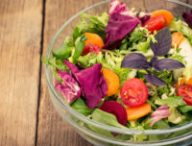 Fresh mixed salad in the bowl on the wooden table