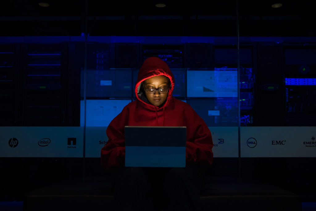 Une femme qui ne pirate probablement pas un réseau WiFi mais qui a une capuche de hackeuse. // Source : WoC In Tech Une femme qui ne pirate probablement pas un réseau WiFi mais qui a une capuche de hackeuse. // Source : WoC In Tech