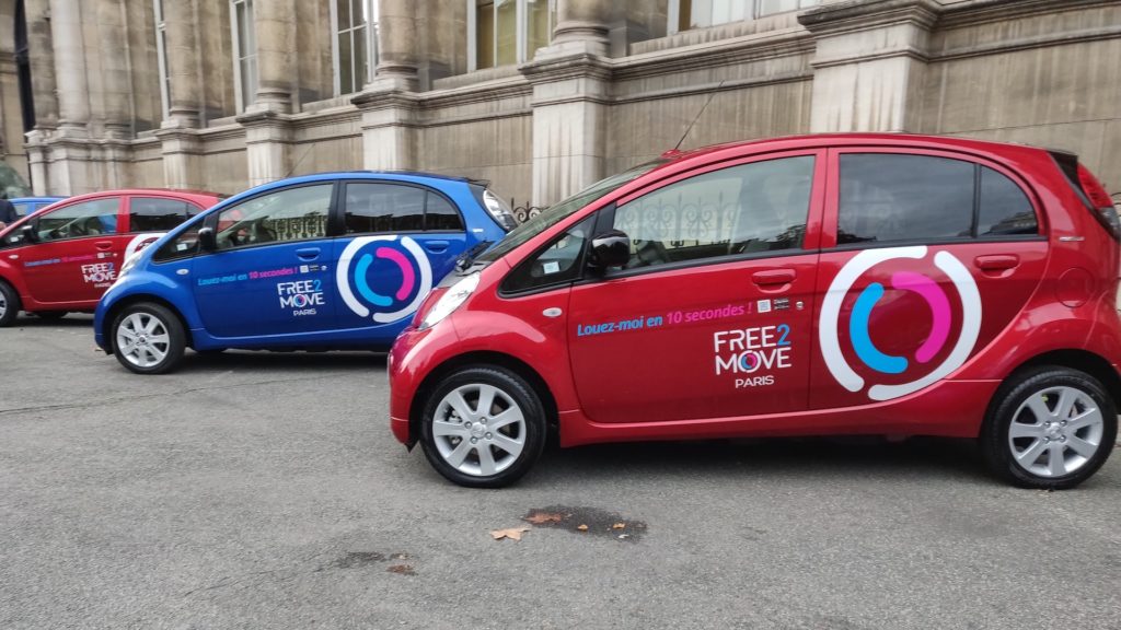 Les voitures bleues et rouges de Free2Move étaient exposées à l'extérieur de l'hôtel de ville de Paris. // Source : Numerama Les voitures bleues et rouges de Free2Move étaient exposées à l'extérieur de l'hôtel de ville de Paris. // Source : Numerama