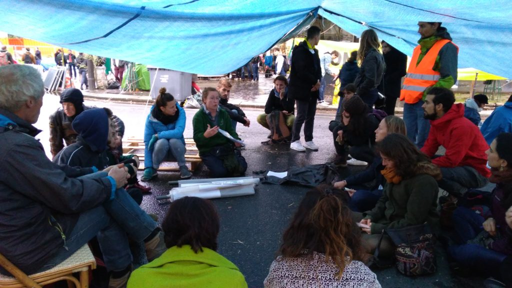 Les « zadistes » d'XR se rassemblent sous des tentes pour suivre des conférences durant lesquelles des organisateurs leur parle des objectifs du mouvement et les forment à la communication. // Source : Numerama Les « zadistes » d'XR se rassemblent sous des tentes pour suivre des conférences durant lesquelles des organisateurs leur parle des objectifs du mouvement et les forment à la communication. // Source : Numerama