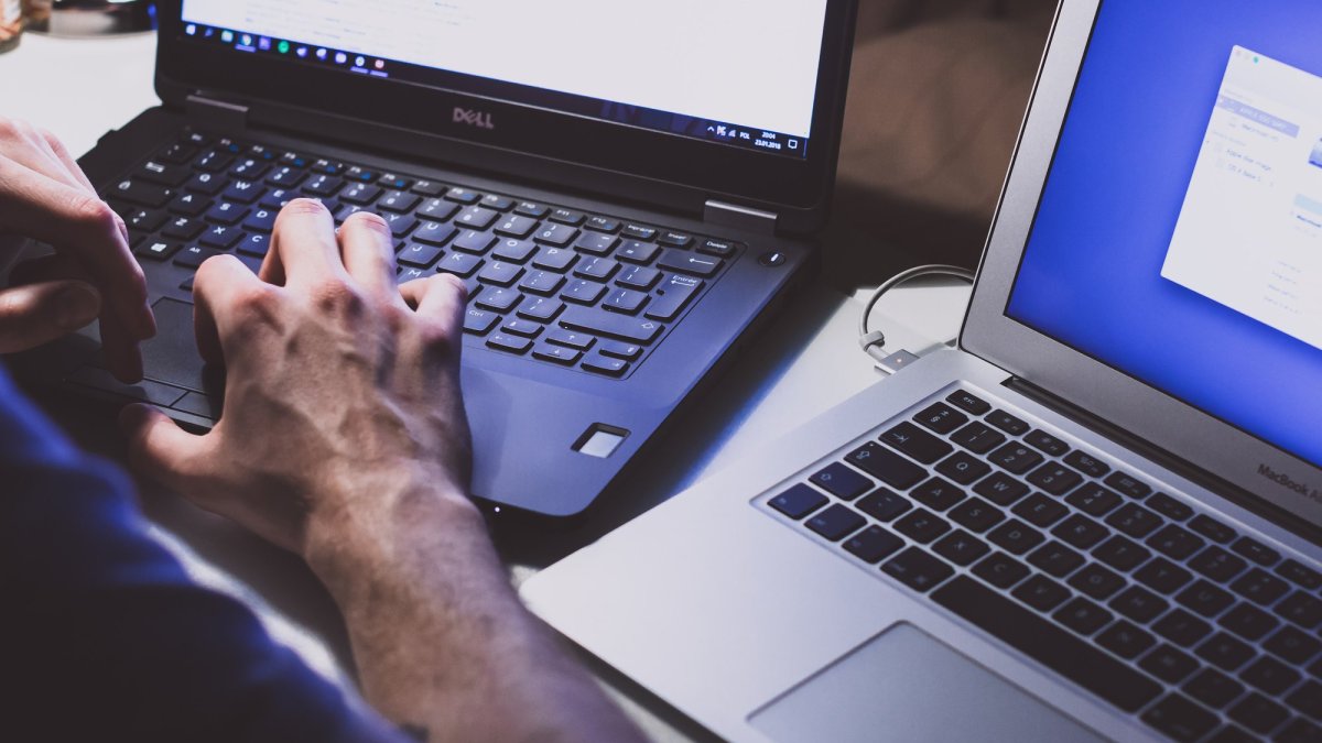 Un homme avec des mains de hacker et deux ordinateurs (probablement avec des malwares) // Source : Freestocks.org via Unsplash Un homme avec des mains de hacker et deux ordinateurs (probablement avec des malwares) // Source : Freestocks.org via Unsplash