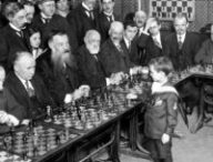 Une photo de Samuel Reshevsky, génie des échecs, prise en 1920 alors qu'il fait des parties simultanées avec des adultes (qu'il a probablement battu). // Source : Wikipedia