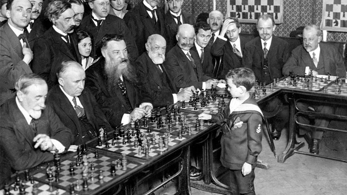 Une photo de Samuel Reshevsky, génie des échecs, prise en 1920 alors qu'il fait des parties simultanées avec des adultes (qu'il a probablement battu). // Source : Wikipedia Une photo de Samuel Reshevsky, génie des échecs, prise en 1920 alors qu'il fait des parties simultanées avec des adultes (qu'il a probablement battu). // Source : Wikipedia