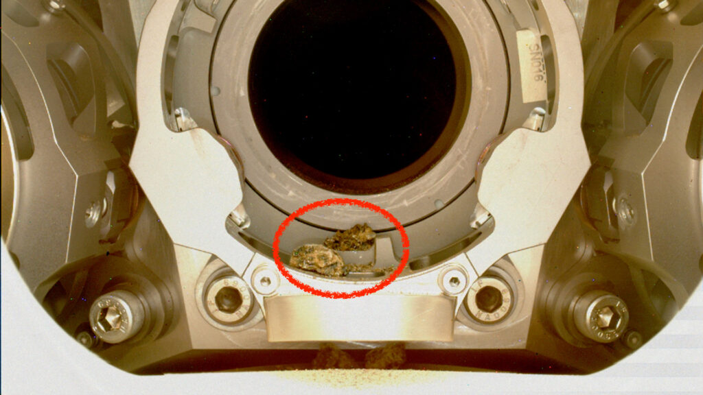 Les débris coincés dans le système d'échantillonnage du rover. // Source : NASA/JPL-Caltech/MSSS (photo recadrée et annotée) Les débris coincés dans le système d'échantillonnage du rover. // Source : NASA/JPL-Caltech/MSSS (photo recadrée et annotée)