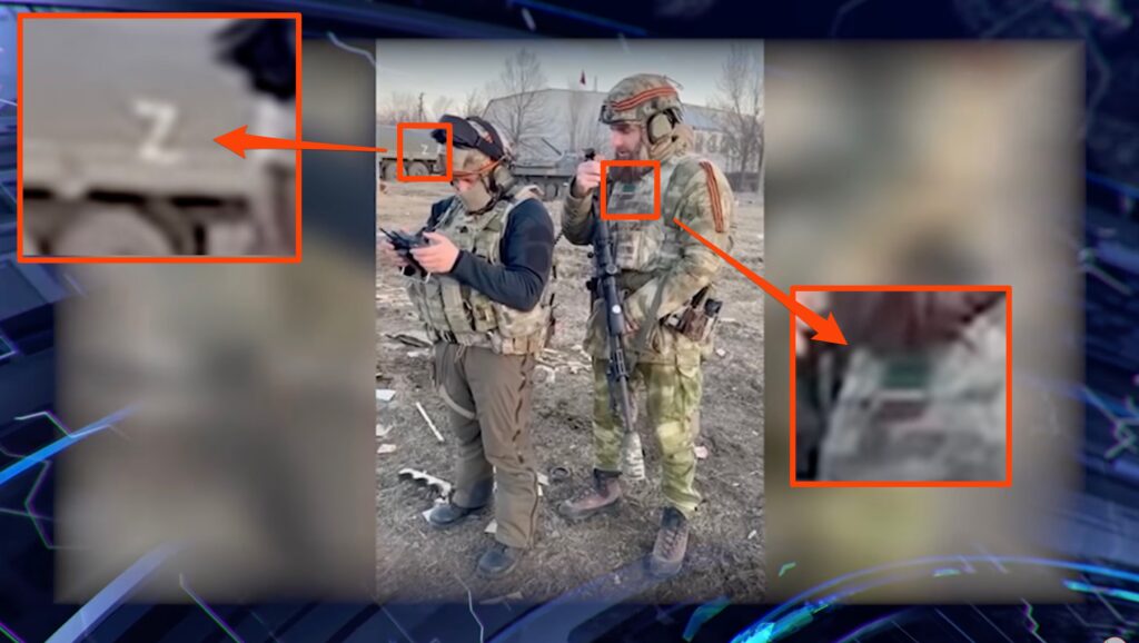Le Z sur un char dans le fond fait penser à une association avec les troupes russes, tandis que le drapeau sur la droite est celui de la Tchétchénie // Source : YouTube/КалемПир ТВ Le Z sur un char dans le fond fait penser à une association avec les troupes russes, tandis que le drapeau sur la droite est celui de la Tchétchénie // Source : YouTube/КалемПир ТВ