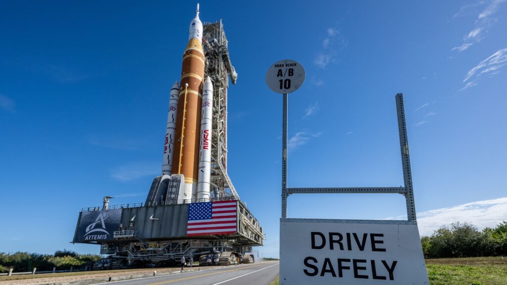 Le SLS roule vers le pas de tir pour la mission Artémis II. // Source : Flickr/Nasa HQ Photos (image modifiée) Le SLS roule vers le pas de tir pour la mission Artémis II. // Source : Flickr/Nasa HQ Photos (image modifiée)