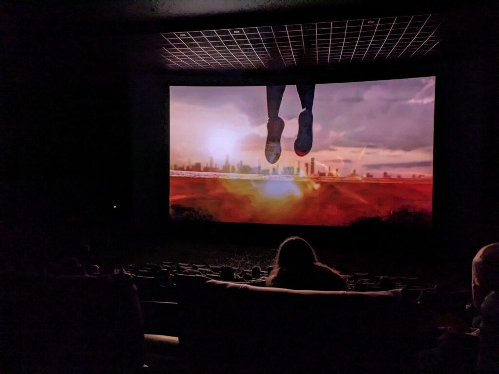 Cette photo a été prise dans le noir complet, avec un écran en mouvement. Le Pixel 7a réussit à voir les sièges de la salle et a arrêté la projection. // Source : Numerama Cette photo a été prise dans le noir complet, avec un écran en mouvement. Le Pixel 7a réussit à voir les sièges de la salle et a arrêté la projection. // Source : Numerama