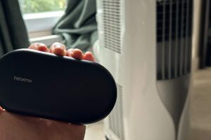 Le contrôle de clim connecté par Netatmo, à côté d'un climatiseur portable. // Source : Numerama Le contrôle de clim connecté par Netatmo, à côté d'un climatiseur portable. // Source : Numerama