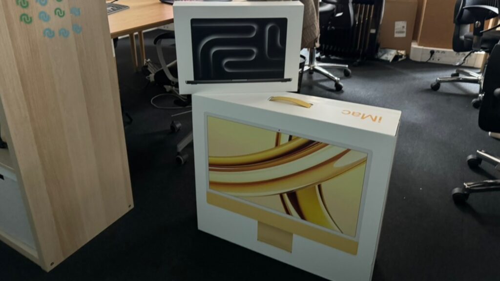 La boîte du MacBook Pro noir sidéral en haut, celle de l'iMac jaune en bas. La boîte du MacBook Pro noir sidéral en haut, celle de l'iMac jaune en bas.