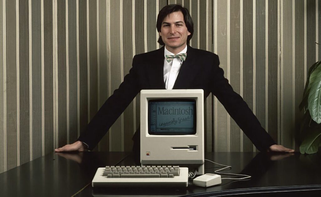 Steve Jobs et le Macintosh en 1984. // Source : Apple Steve Jobs et le Macintosh en 1984. // Source : Apple