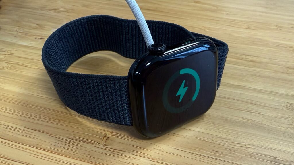 L'Apple Watch Series 10, version Jet Black, sur son chargeur. L'Apple Watch Series 10, version Jet Black, sur son chargeur.