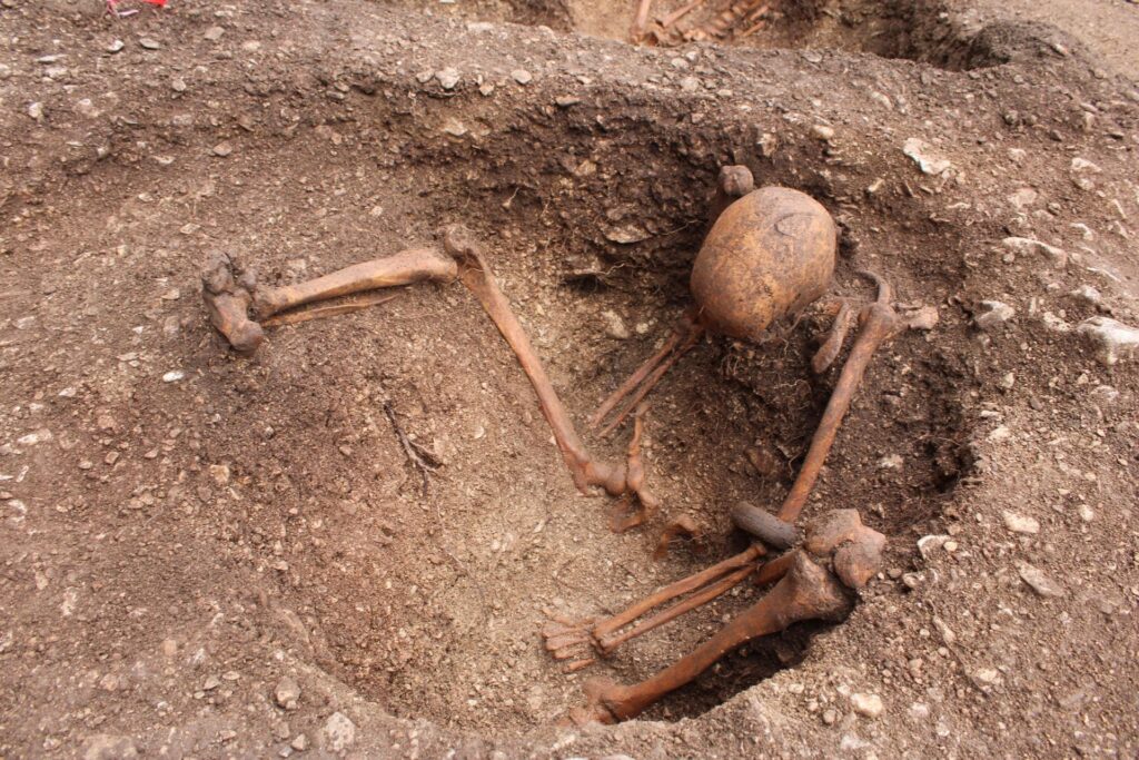Inhumation d'un homme assis avec des stigmates d'une blessure au crâne et portant un bracelet en roche noire // Source : Hervé Laganier, Inrap Inhumation d'un homme assis avec des stigmates d'une blessure au crâne et portant un bracelet en roche noire // Source : Hervé Laganier, Inrap