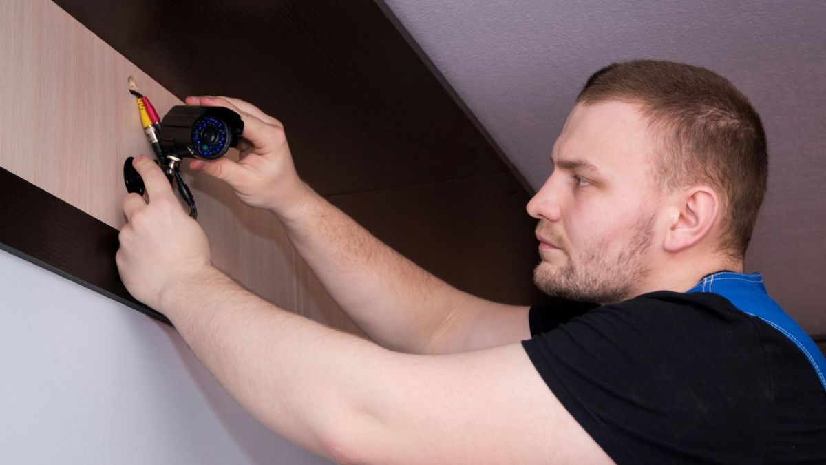 Un homme installe une caméra de surveillance // Source : Bermix Studio via Unsplash Un homme installe une caméra de surveillance // Source : Bermix Studio via Unsplash