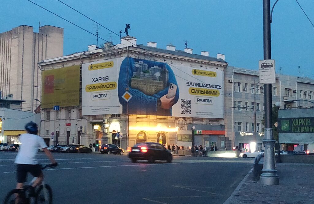 « Kharkiv, serrons-nous les coudes / Restons forts ensemble. » Publicité des magasins de smartphones Yabluka (« pommes » en ukrainien). Kharkiv subit des raids aériens cinq à dix fois par jour en moyenne depuis trois ans et demi. « Kharkiv, serrons-nous les coudes / Restons forts ensemble. » Publicité des magasins de smartphones Yabluka (« pommes » en ukrainien). Kharkiv subit des raids aériens cinq à dix fois par jour en moyenne depuis trois ans et demi.