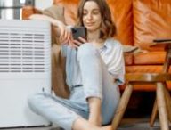 Une personne assise à côté d'un climatiseur. // Source : Envato
