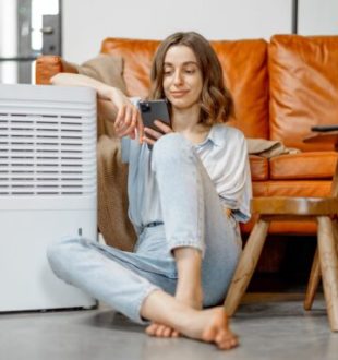 Une personne assise à côté d'un climatiseur. // Source : Envato Une personne assise à côté d'un climatiseur. // Source : Envato