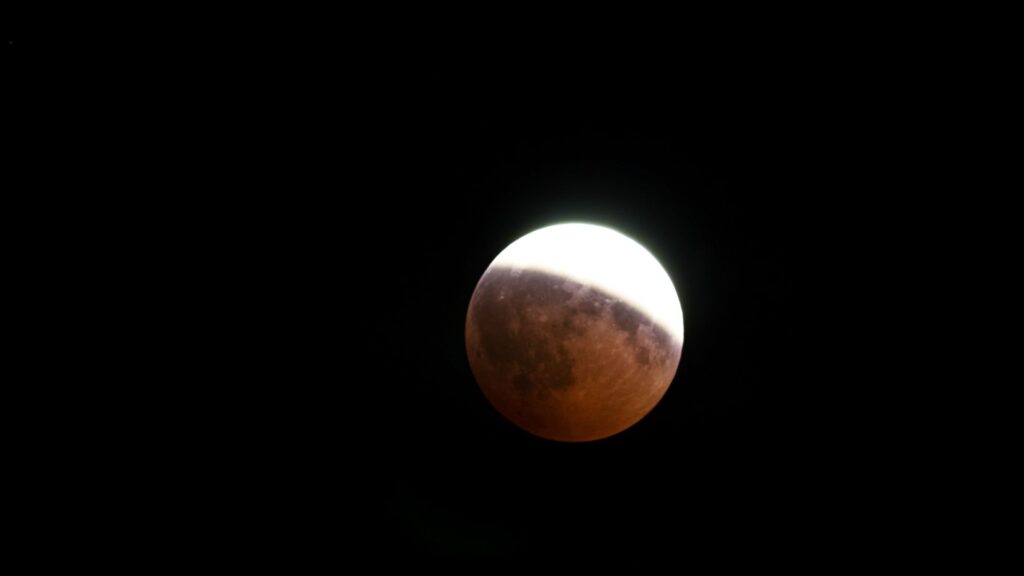 Éclipse partielle de Lune, seule la partie de l'astre se trouvant dans l'ombre prendre une teinte rougeatre. // Source : Canva Éclipse partielle de Lune, seule la partie de l'astre se trouvant dans l'ombre prendre une teinte rougeatre. // Source : Canva