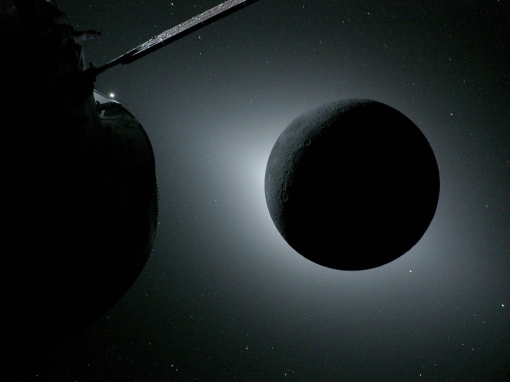 art002e009571 (April 6, 2026) - The Moon, backlit by the Sun during a solar eclipse, is photographed by NASA’s Orion spacecraft on April 6, 2026, during the Artemis II mission. Orion is visible in the foreground on the left. Earth is reflecting sunlight at the left edge of the Moon, which is slightly brighter than the rest of the disk. The bright spot visible just below the Moon’s bottom right edge is Saturn. Beyond that, the bright spot at the right edge of the image is Mars. Credit: NASA art002e009571 (April 6, 2026) - The Moon, backlit by the Sun during a solar eclipse, is photographed by NASA’s Orion spacecraft on April 6, 2026, during the Artemis II mission. Orion is visible in the foreground on the left. Earth is reflecting sunlight at the left edge of the Moon, which is slightly brighter than the rest of the disk. The bright spot visible just below the Moon’s bottom right edge is Saturn. Beyond that, the bright spot at the right edge of the image is Mars. Credit: NASA